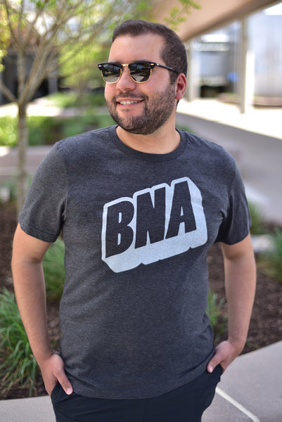 A male model wears the Upward Dark Gray T-Shirt outdoors at BNA.