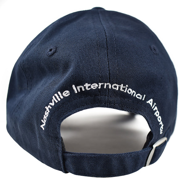 Detail shot of back embroidery.  Navy blue hat with Nashville International Airport embroidered in white , arching over back opening of ballcap.  Hat features adjustable fabric tab with pewter buckle