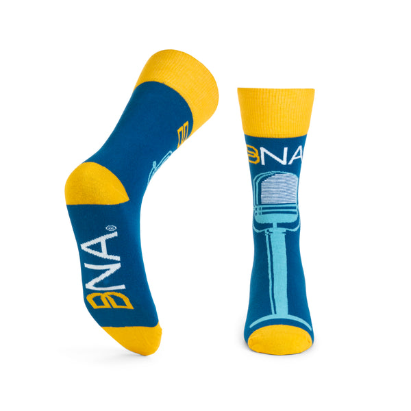 Bottom and Front view of BNA Microphone Socks.  Dark blue socks with yellow cuffs, heels, and toes.  Features the BNA logo above a teal vintage microphone design vertically down the front of the socks.  BNA logo on the sole.
