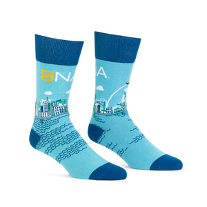 Nashville cityscape design on light blue background and dark blue cuffs, heels, and toes.  BNA logo across the back of the sock with the skyline and water wrapping around.  