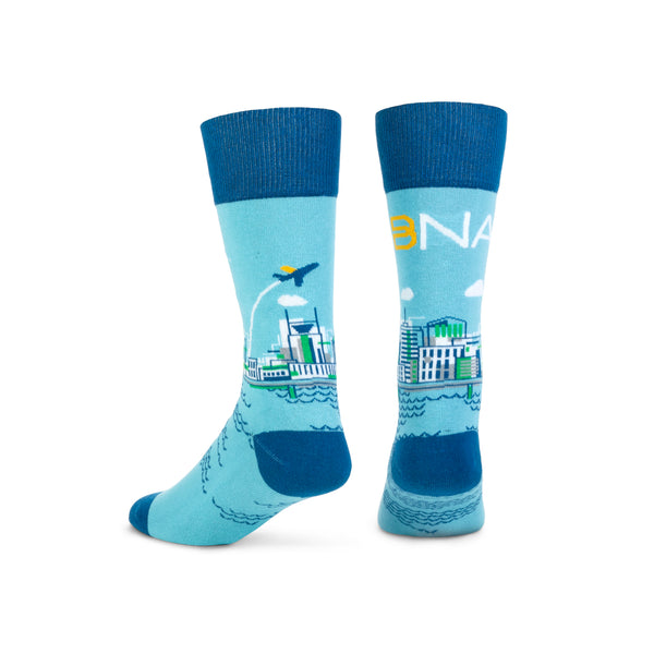 Nashville cityscape design on light blue background and dark blue cuffs, heels, and toes.  BNA logo across the back of the sock with the skyline and water wrapping around.  