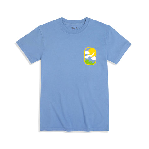 Front view of Travel Adventure Fun Tee.  Washed Denim Comfort Colors unisex tee features front left chest graphic.  Design is a whimsical illustration with a sun, clouds, a plane wing, and hills.  Like peeking out of the window of a plane.