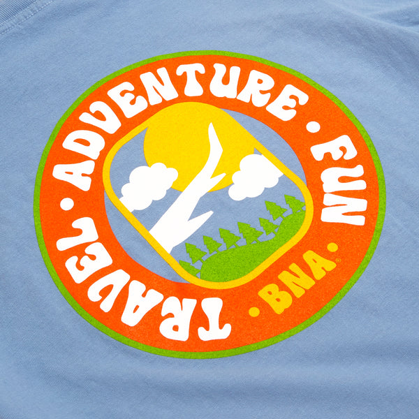 Back detail view of Travel Adventure Fun Tee. Washed Denim Comfort Colors unisex tee back graphic features larger version of front illustration encased in a playful circular border that reads "Travel. Adventure. Fun. BNA."  