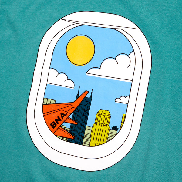 Detailed view of seafoam teal t-shirt with center front graphic depicting an illustrated view of a window seat and the view outside with sun, clouds, and Nashville's skyline.  The wing of a plane with BNA painted completes the picture.