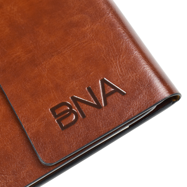 Detail shot of embossed BNA logo on cover of cognac faux leather portfolio