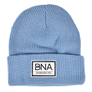 Light blue waffle knit beanie with white woven label on cuff.  Label features black border and BNA logo above "established 1937".